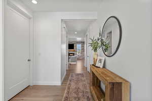 Corridor with light wood-style floors, baseboards, and recessed lighting