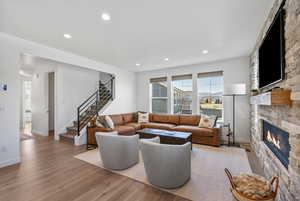 Living room featuring a fireplace, recessed lighting, baseboards, wood finished floors, and stairway