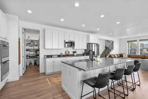 Kitchen with a kitchen bar, appliances with stainless steel finishes, light wood-type flooring, a sink, and open floor plan