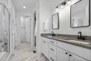 Bathroom with a sink, baseboards, a stall shower, and double vanity