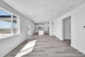 Unfurnished living room with an inviting chandelier, light wood-style floors, recessed lighting, baseboards, and visible vents