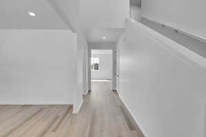 Hallway with light wood-style floors, baseboards, and recessed lighting