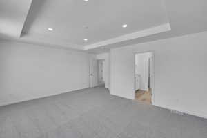 Unfurnished bedroom featuring visible vents, baseboards, light colored carpet, recessed lighting, and a tray ceiling