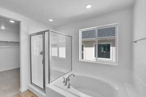 Bathroom featuring a garden tub, recessed lighting, a walk in closet, and a stall shower