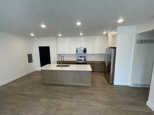 Kitchen with dark wood-style flooring, a sink, stainless steel appliances, decorative backsplash, and visible vents