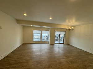 Unfurnished room featuring visible vents, baseboards, dark wood-style floors, a notable chandelier, and recessed lighting