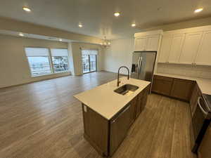 Kitchen with a chandelier, wood finished floors, a sink, open floor plan, and stainless steel fridge
