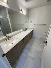 Bathroom with double vanity, a shower stall, a sink, toilet, and marble finish floor