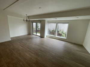 Unfurnished room featuring baseboards, a chandelier, dark wood-style floors, and visible vents