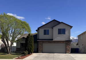 Traditional-style home featuring fence, stone siding, a garage, a gate, and driveway