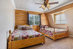 Bedroom featuring carpet flooring, a ceiling fan, baseboards, rustic walls, and ornamental molding