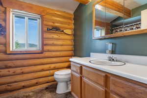 Bathroom with toilet, rustic walls, and plenty of natural light