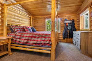 Bedroom with log walls, carpet, and wood ceiling