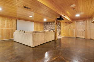 Living room with wooden walls, finished concrete floors, and visible vents