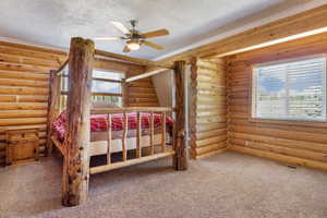 Unfurnished bedroom featuring rustic walls, carpet flooring, a textured ceiling, and visible vents