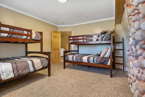 Carpeted bedroom featuring crown molding, a textured ceiling, and baseboards