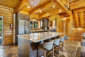 Kitchen with log walls, wood ceiling, stainless steel appliances, and beamed ceiling