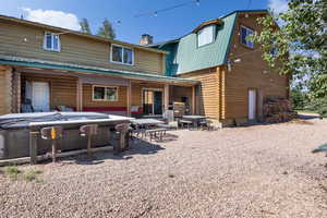 Back of property featuring a gambrel roof, a patio area, log exterior, metal roof, and a hot tub