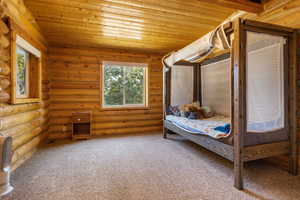 Bedroom featuring rustic walls, multiple windows, and wooden ceiling