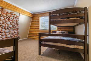 Carpeted bedroom featuring baseboards, ornamental molding, and rustic walls