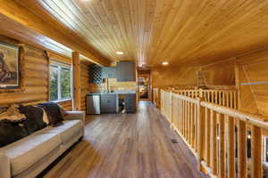 Living room featuring wooden ceiling, log walls, recessed lighting, and wood finished floors