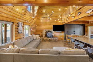 Living room featuring wood ceiling, a towering ceiling, a wood stove, beamed ceiling, and rustic walls
