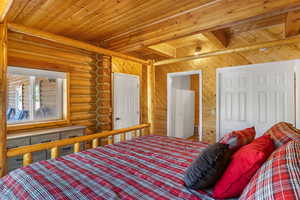 Bedroom with wood ceiling, rustic walls, and beam ceiling