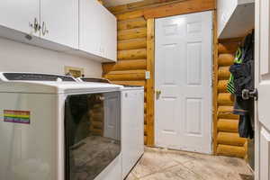 Laundry room featuring log walls, cabinet space, and independent washer and dryer