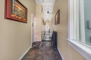 Corridor with baseboards and stone finish floor