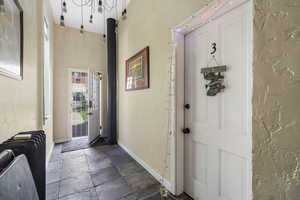 Entrance foyer featuring stone tile flooring, baseboards, and a textured wall
