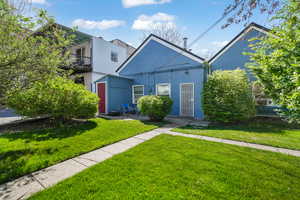 View of front of home with a balcony, a front yard, and stucco siding