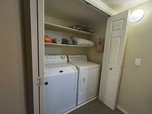 Laundry room featuring baseboards, laundry area, washer and clothes dryer, and dark colored carpet