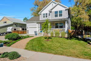 View of front facade featuring a garage, a front lawn, fence, covered porch, and board and batten siding