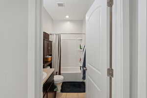 Bathroom featuring visible vents, tile patterned flooring, vanity, toilet, and shower / tub combo with curtain