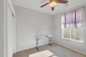 Carpeted office space featuring visible vents, a ceiling fan, and baseboards