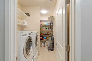 Laundry area with laundry area, washer and clothes dryer, light tile patterned flooring, and visible vents