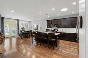 Kitchen featuring a kitchen breakfast bar, appliances with stainless steel finishes, and hardwood / wood-style floors
