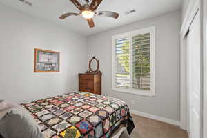 Carpeted bedroom featuring baseboards, a ceiling fan, and visible vents