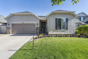 Ranch-style home with a garage, stucco siding, solar panels, and a front yard