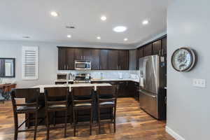 Kitchen featuring wood finished floors, dark brown cabinetry, visible vents, light countertops, and appliances with stainless steel finishes