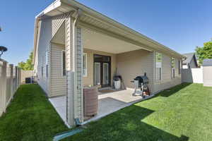 Rear view of house with a lawn, cooling unit, and a fenced backyard