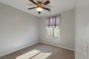 Carpeted empty room with visible vents, baseboards, and a ceiling fan