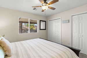 Bedroom with a ceiling fan, two closets, and visible vents