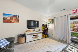 Living area with carpet floors, baseboards, lofted ceiling, and visible vents