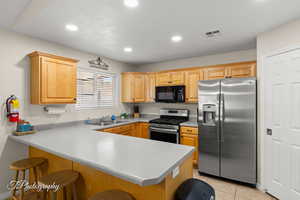 Kitchen with a peninsula, a kitchen bar, recessed lighting, a sink, and stainless steel appliances