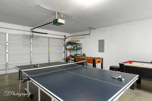 Game room featuring a garage, concrete flooring, and electric panel