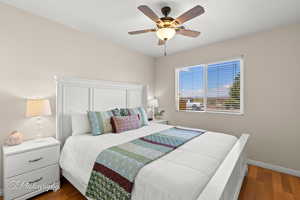 Bedroom with dark wood-style flooring, baseboards, and ceiling fan