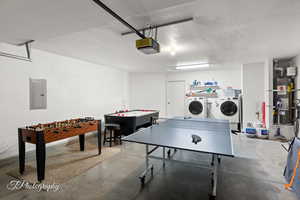 Rec room featuring secured water heater, separate washer and dryer, concrete floors, and electric panel