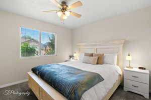 Bedroom featuring a ceiling fan, baseboards, and dark colored carpet