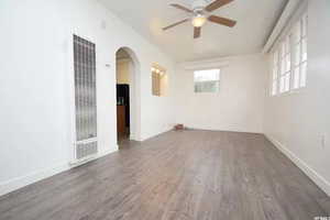 Spare room featuring a heating unit, wood finished floors, baseboards, ceiling fan, and arched walkways